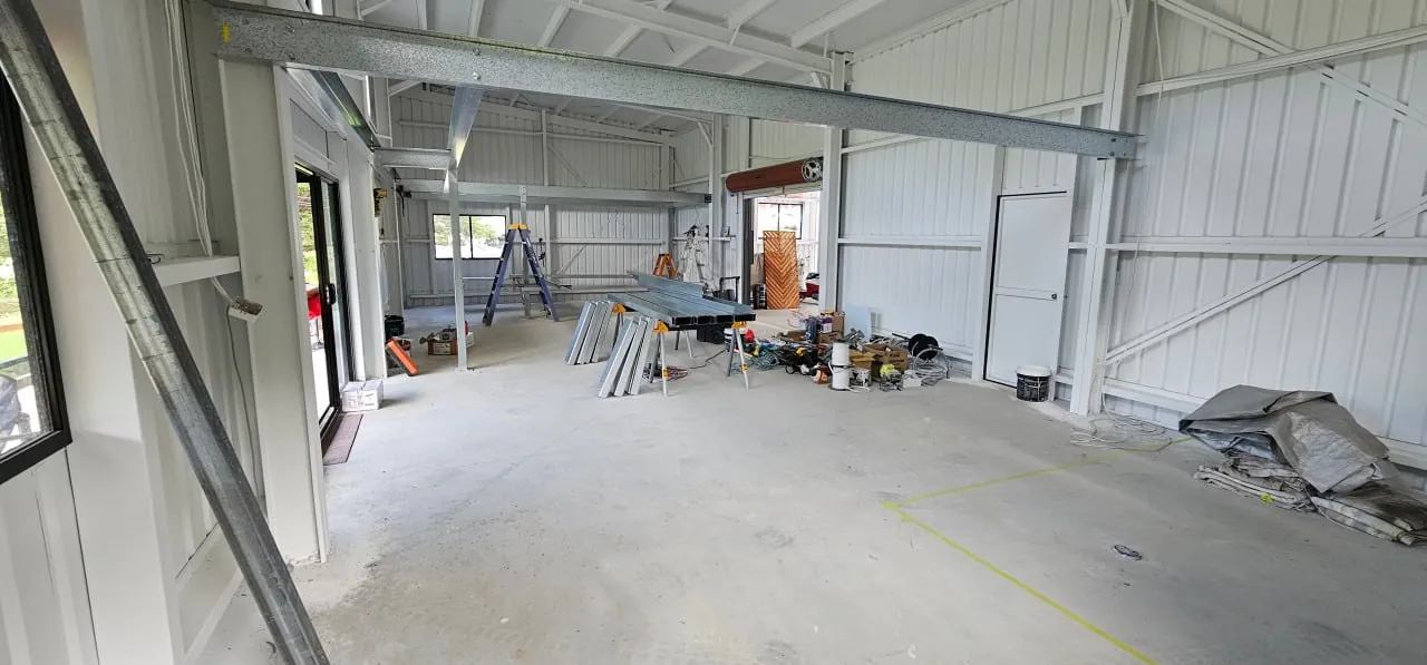 Inside a steel shed with the mezzanine beam fixed across the frame and the floor steel laid out on the slab